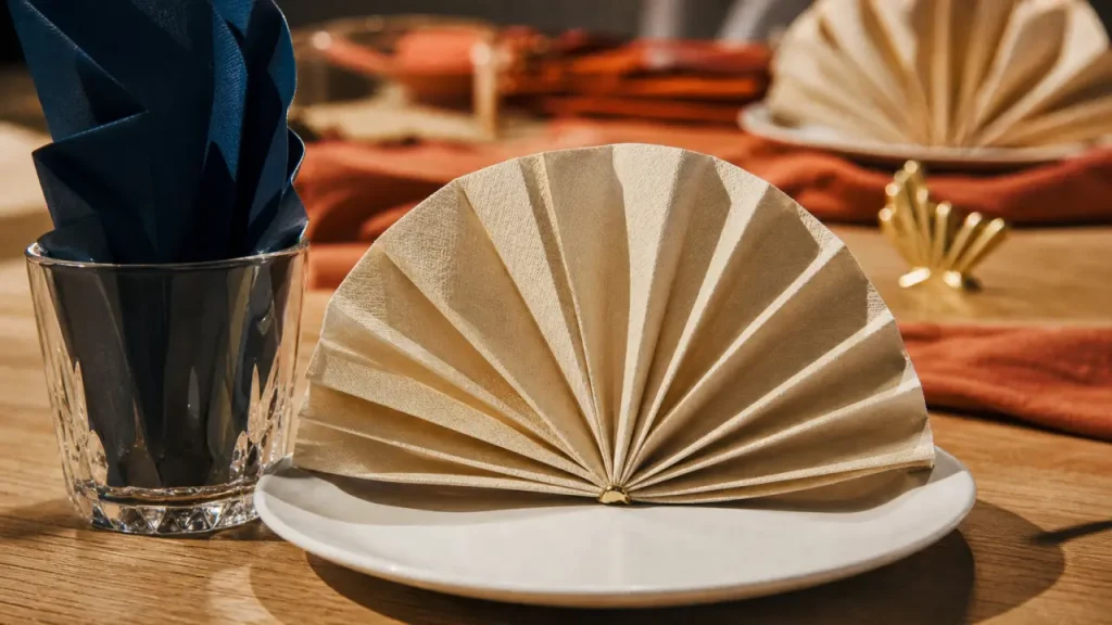 Pliage en serviette en papier facile : serviette beige éventail sur table de fête